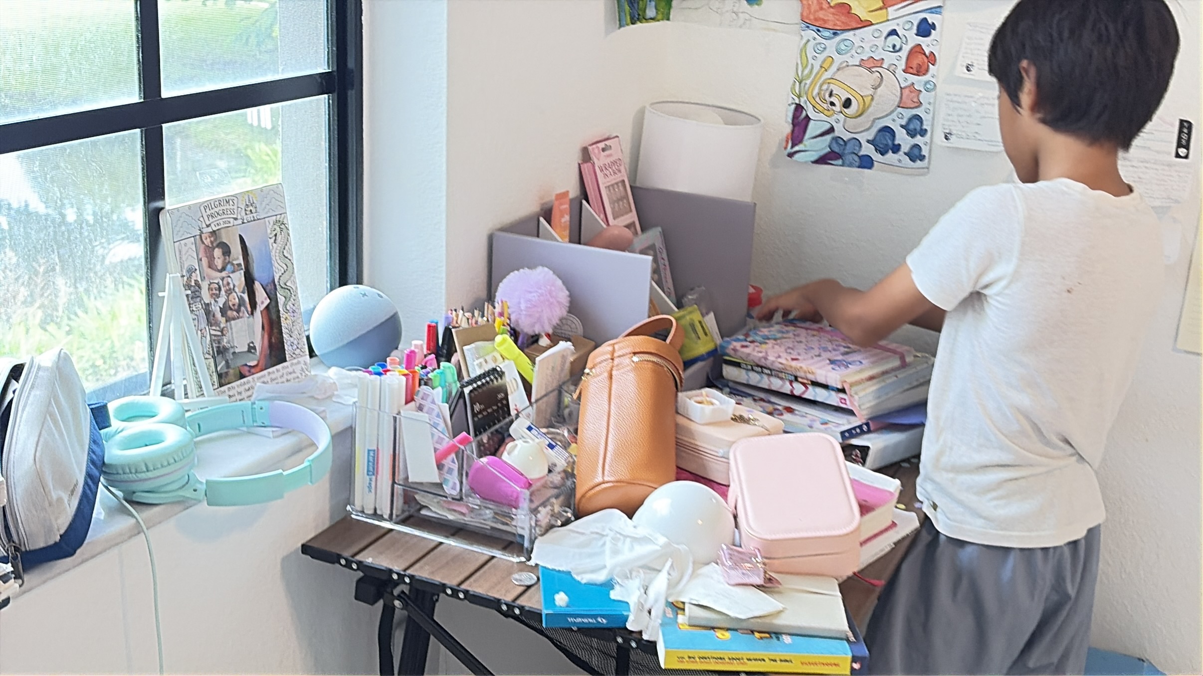 A child sorting books and supplies on a busy desk